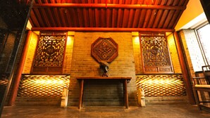 A traditional interior with wooden beams, a brick wall, and decorative screens. - Beijing Traditional View Hotel (Beijing)