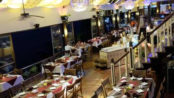 A restaurant with multiple dining tables, chairs, and a staircase leading to an upper level.