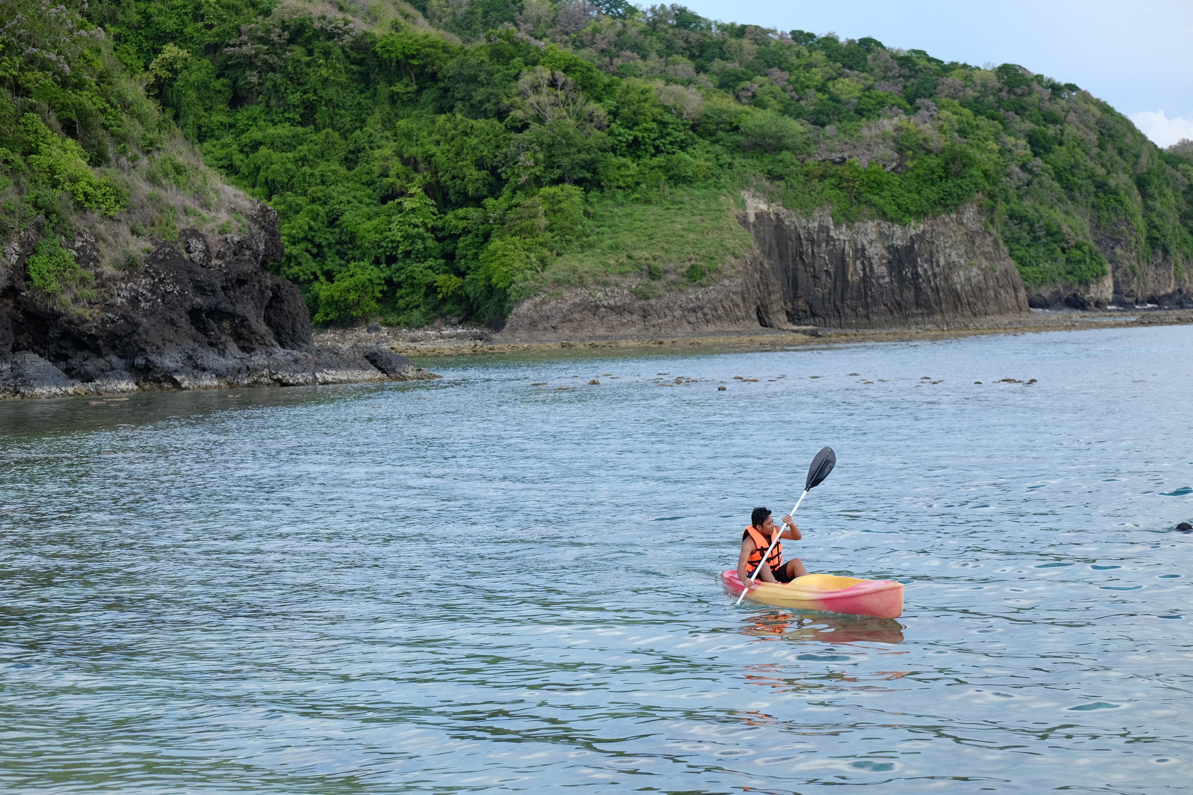 A kayaker in a small, colorful kayak on calm water.