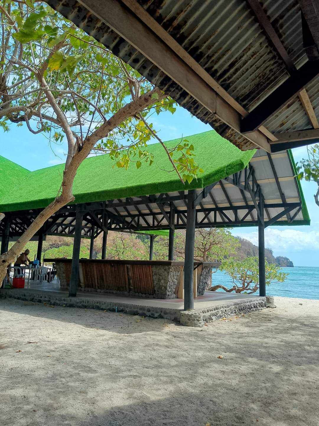 A covered outdoor area with a concrete floor, a wooden structure, and a view of the sea.