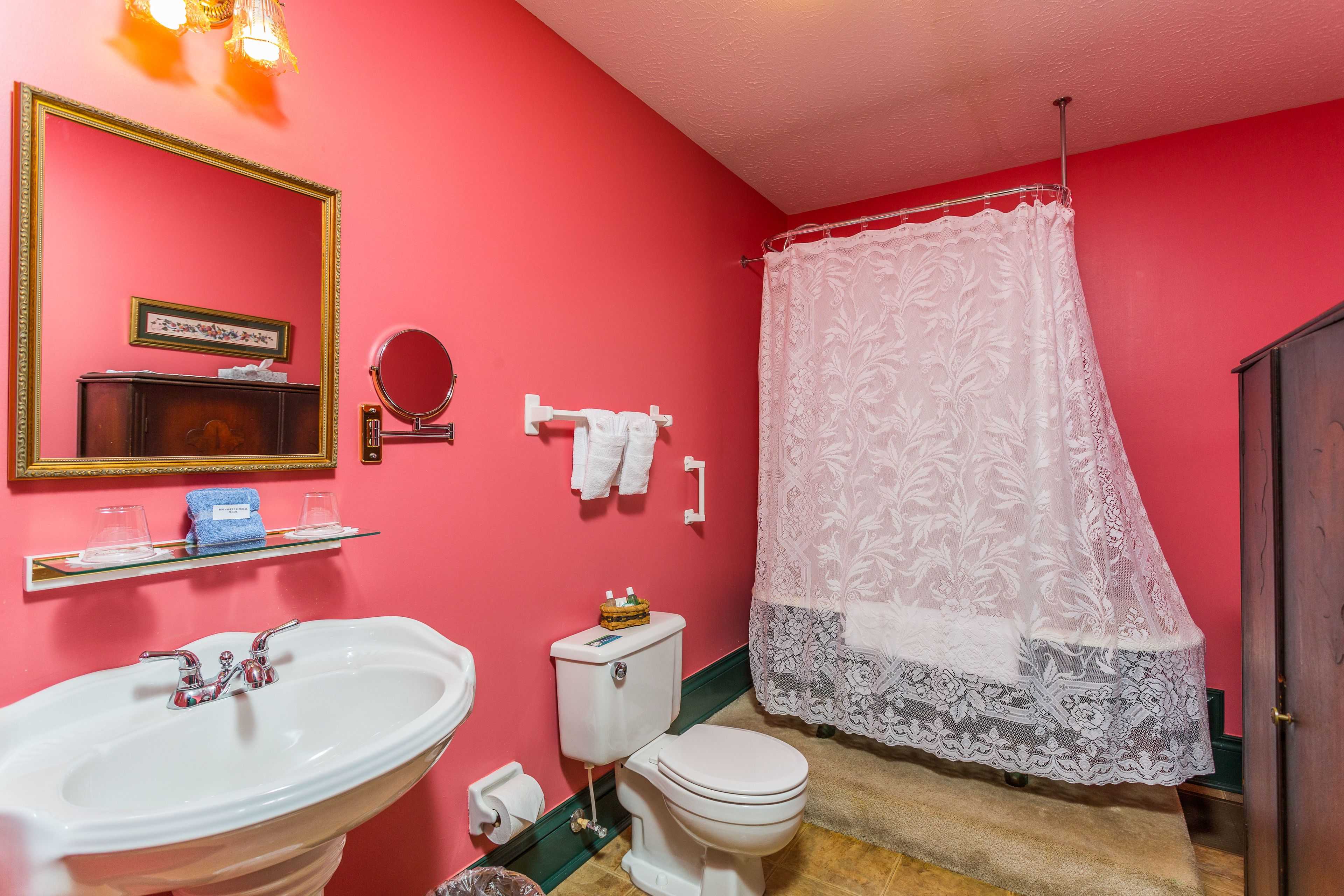 Casa de banho com parede rosa, sanita branca e lavatório.