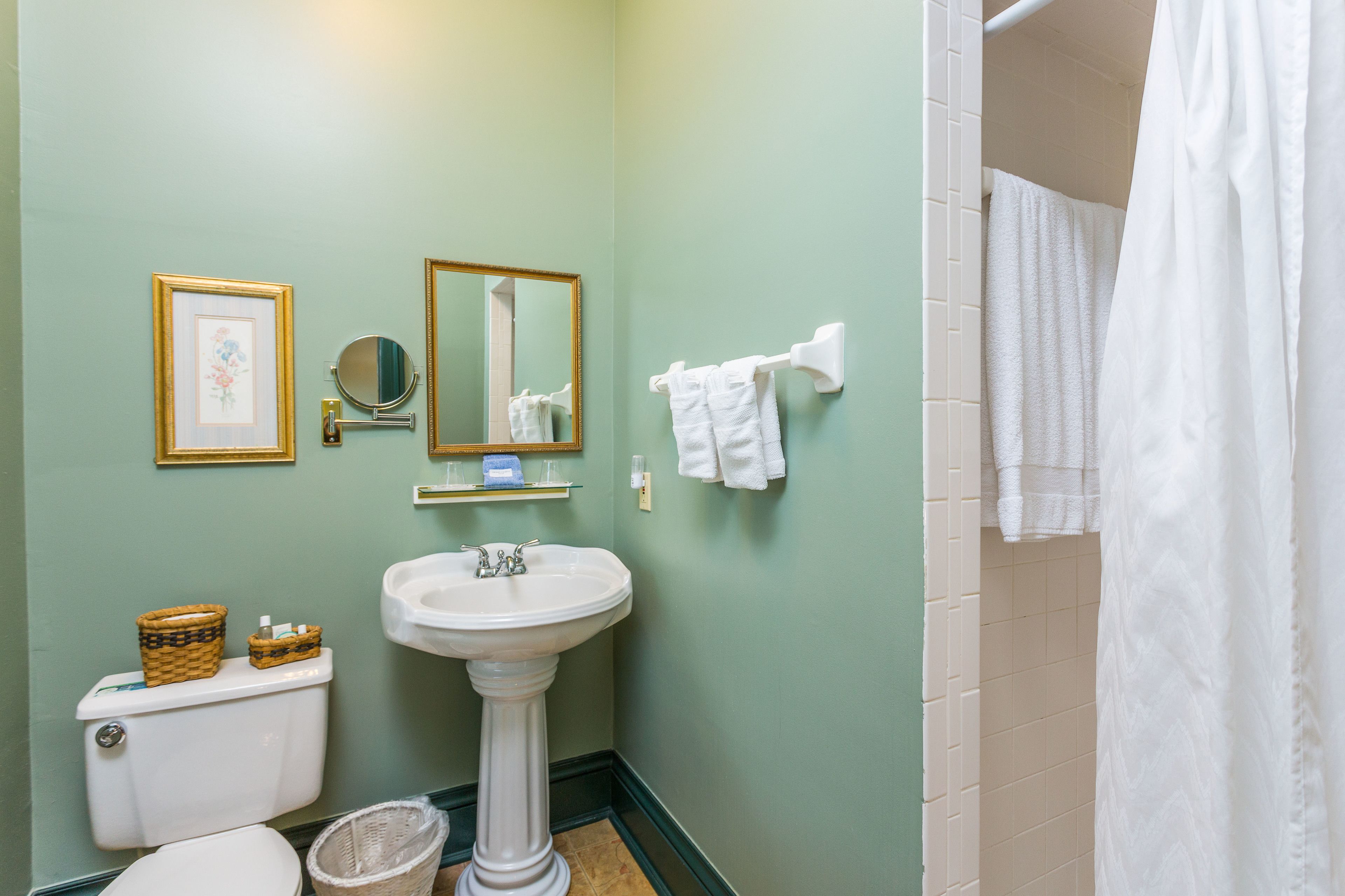 A bathroom with a pedestal sink, toilet, and a shower curtain.