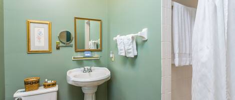 A bathroom with a pedestal sink, toilet, and a shower curtain.