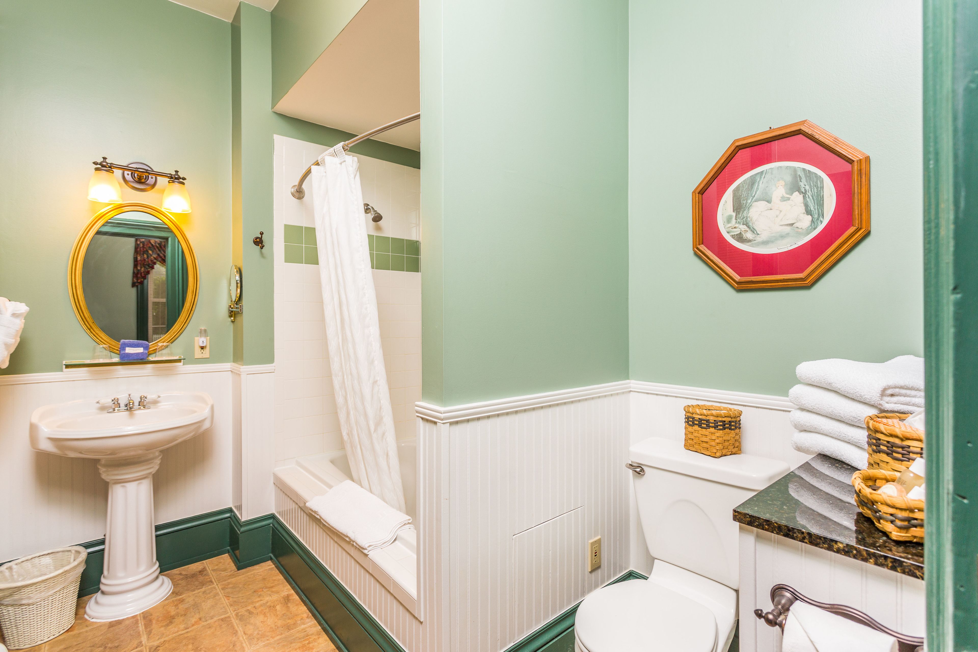 A bathroom with a pedestal sink, white toilet, and a shower curtain.