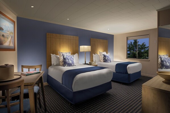 A hotel room with two beds, a desk, and a chair.