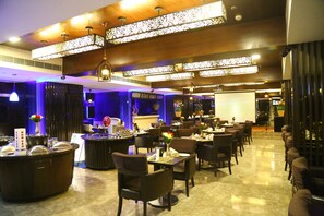 A restaurant with a modern interior, featuring a bar area, multiple dining tables, and a variety of seating options. - Quality Inn Bez Krishnaa (Visakhapatnam)
