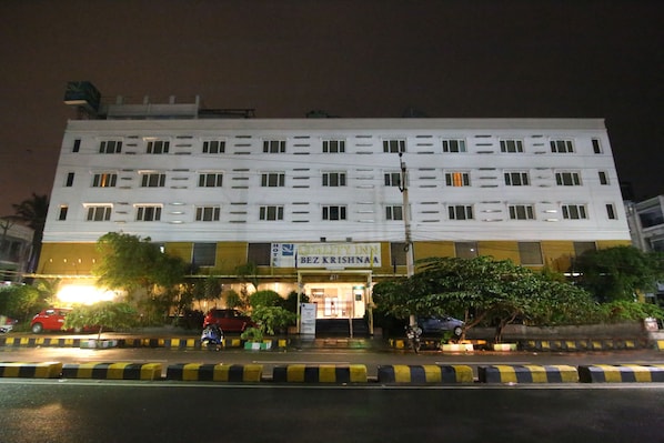 Un hotel con un letrero que dice "Quality Inn" y "Bez Krishna". Tiene varios pisos, una entrada bien iluminada y está rodeado de vegetación.
