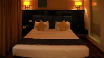 A hotel room with a large bed, two bedside lamps, a headboard, and a view of the outside through a window.