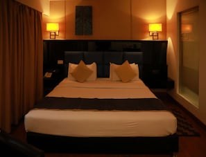 Habitación de hotel con una cama grande, dos lámparas de noche, un cabecero y vistas al exterior a través de una ventana.