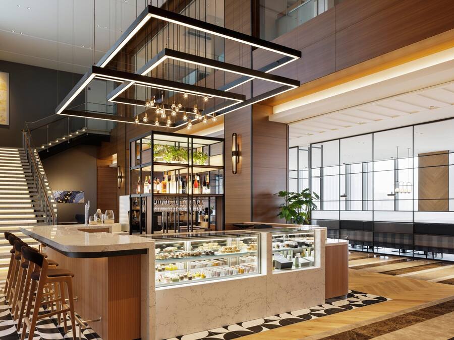 A modern bar area with a marble counter, glass display cases, and a staircase with wooden railings.