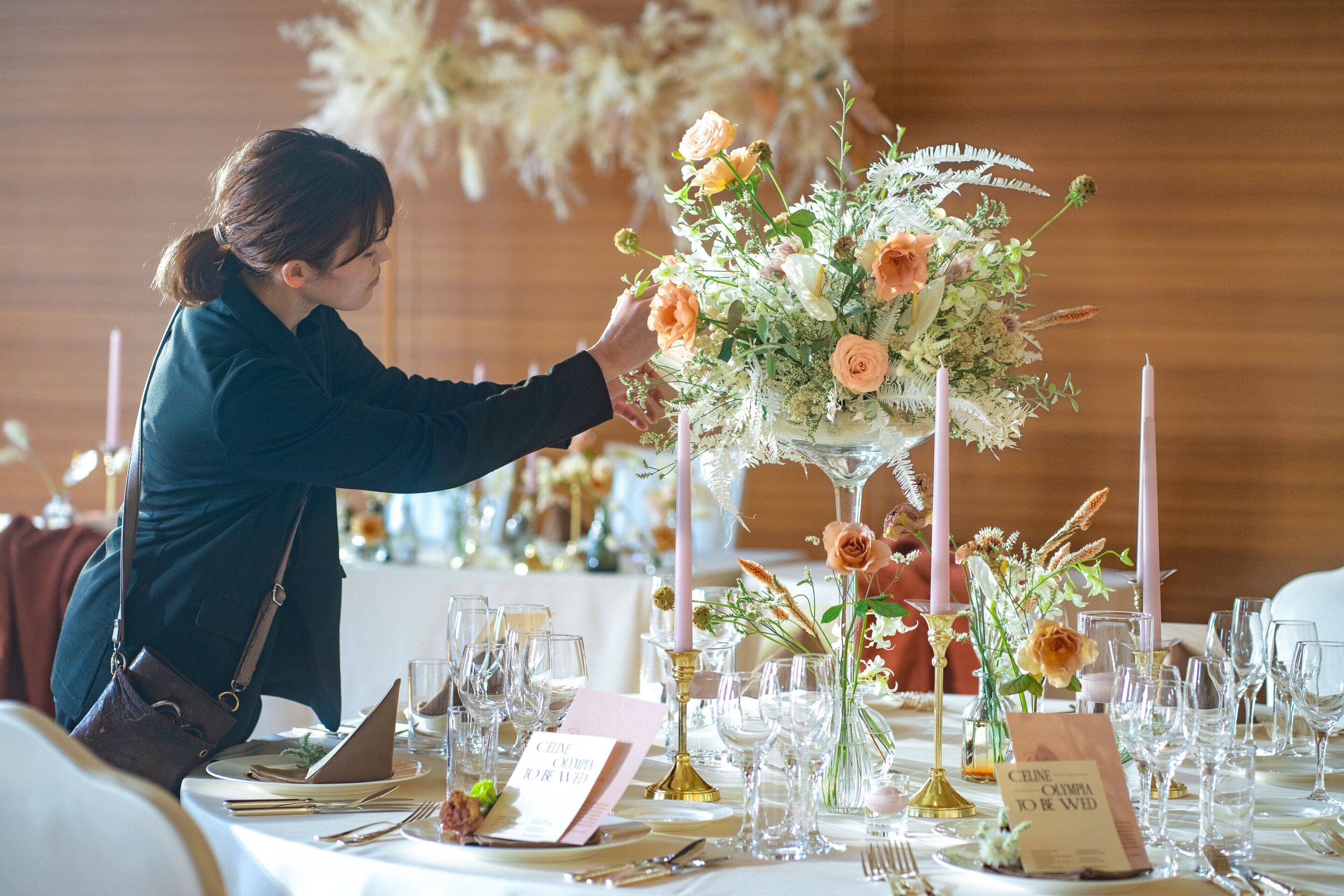 Ein Tisch ist für eine Hochzeitsfeier gedeckt, mit floralen Tischdekorationen, Kerzen und Platzkärtchen.