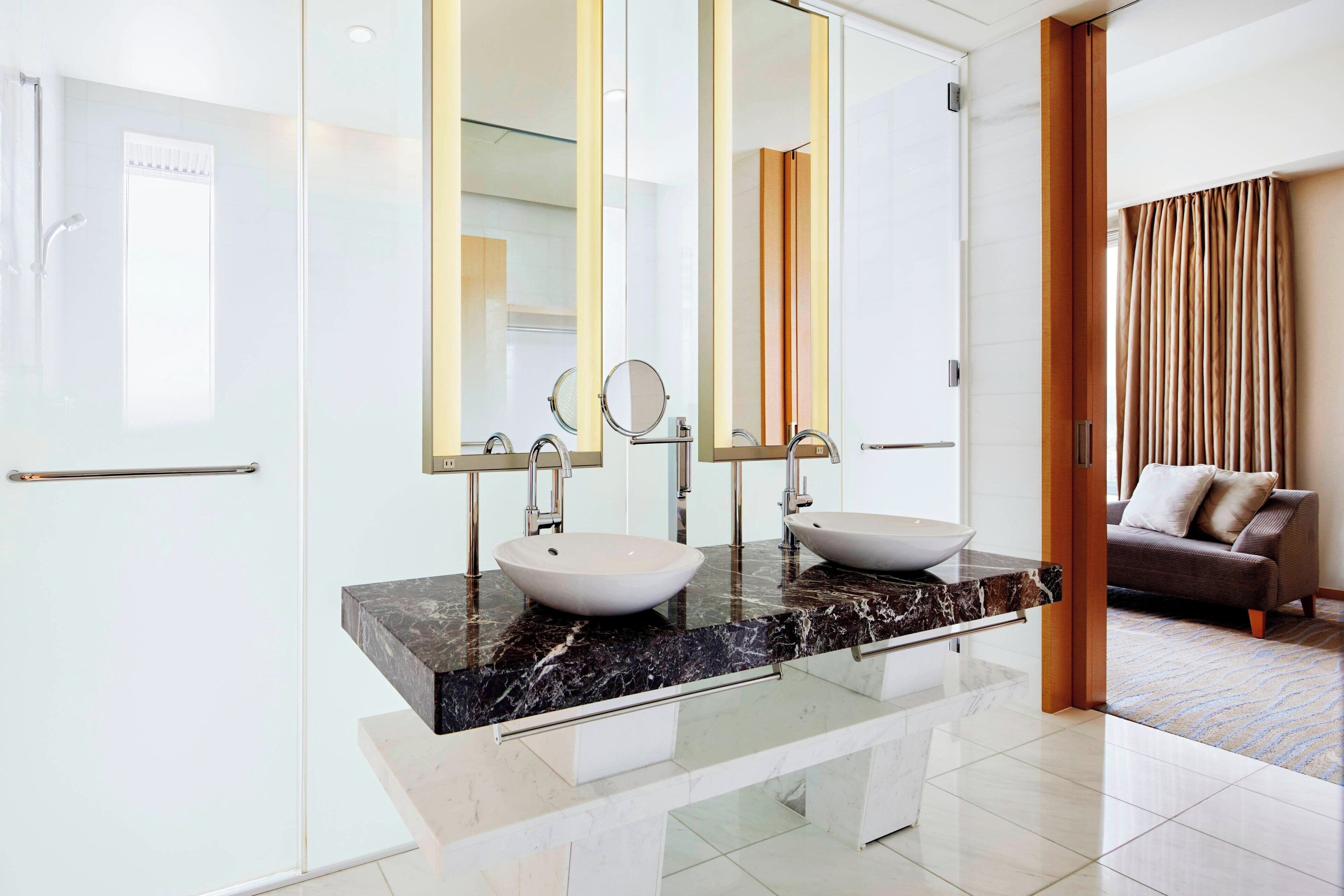 A modern bathroom with two sinks, large mirrors, and a glass shower enclosure.