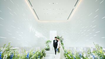 A modern interior with a central aisle, white walls, and ceiling lights.