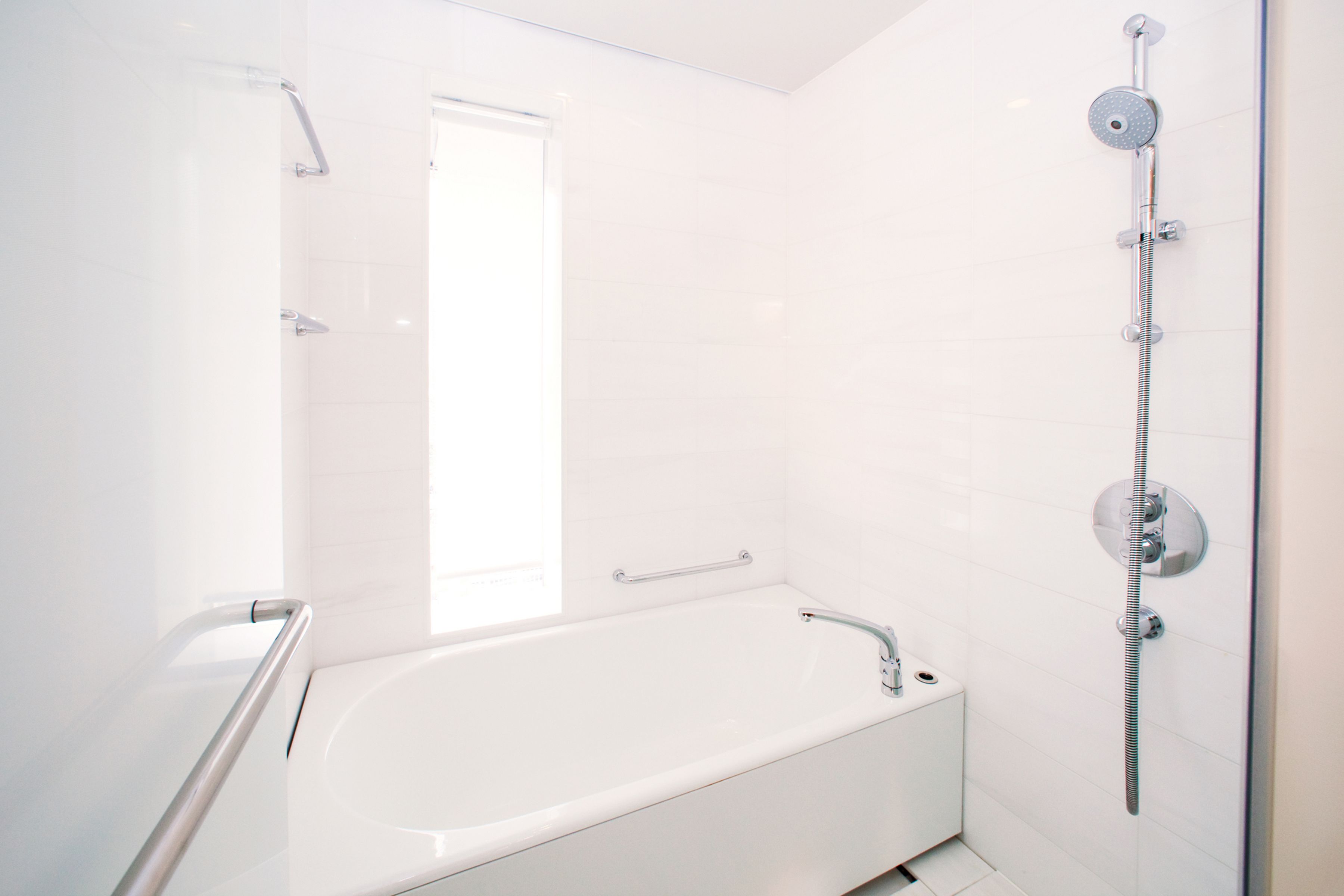 A modern bathroom with a white bathtub, a shower with a handheld showerhead, and a glass shower enclosure.