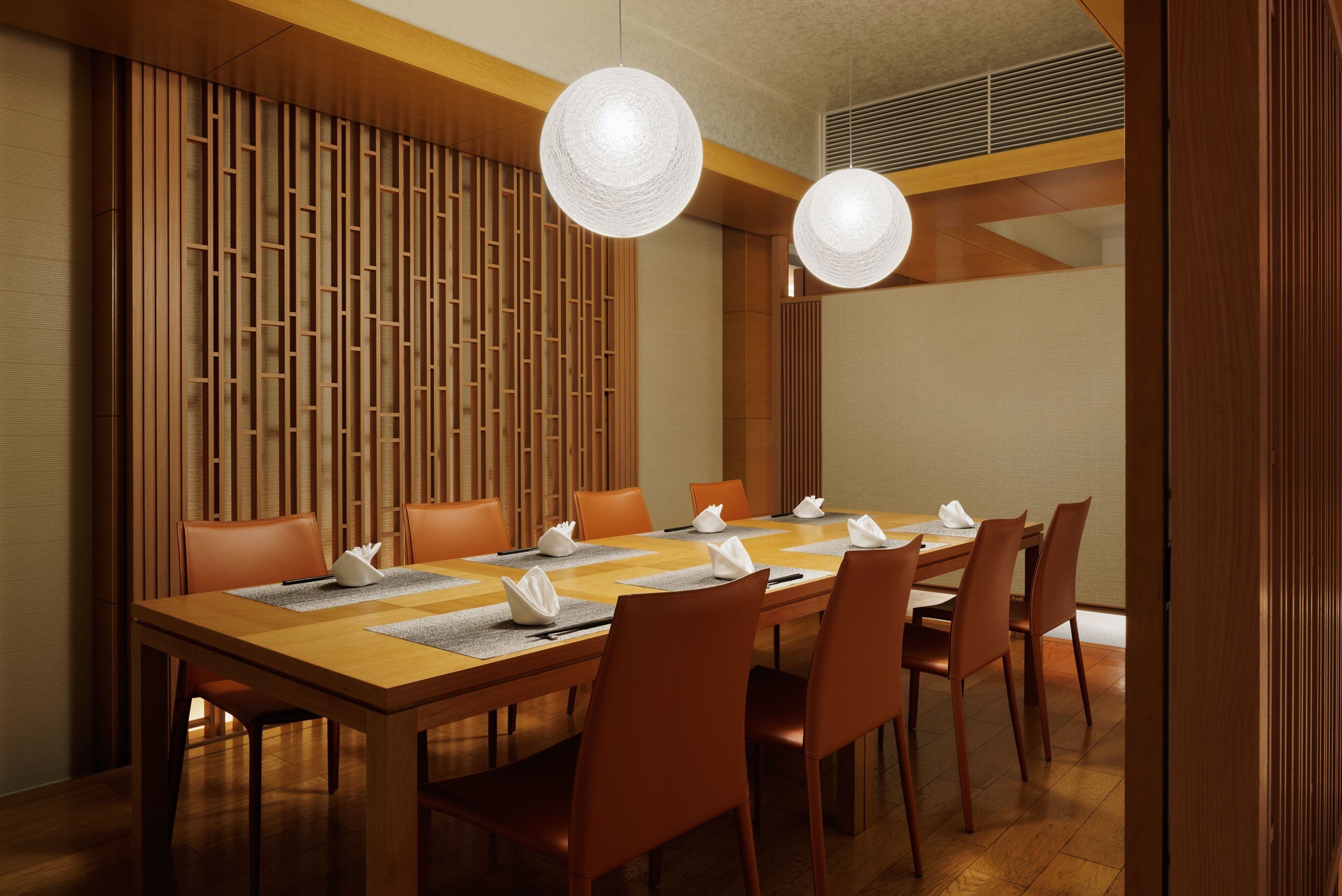 A conference room with a long table, multiple chairs, and two pendant lights.