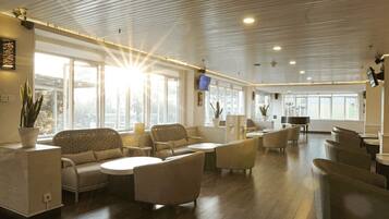 A spacious lobby with a high ceiling, large windows, and a variety of seating arrangements including sofas and chairs.
