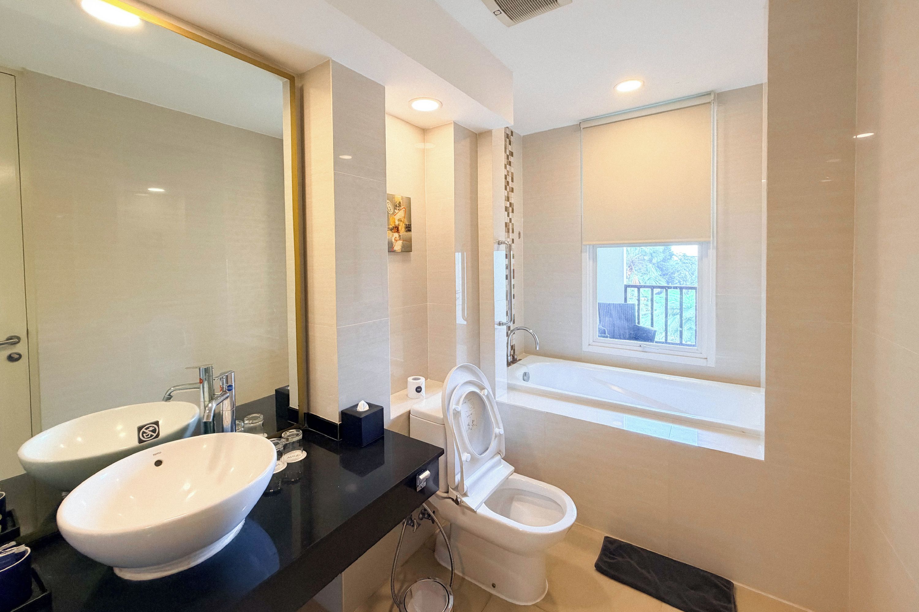 A modern bathroom with two sinks, a toilet, and a bathtub.