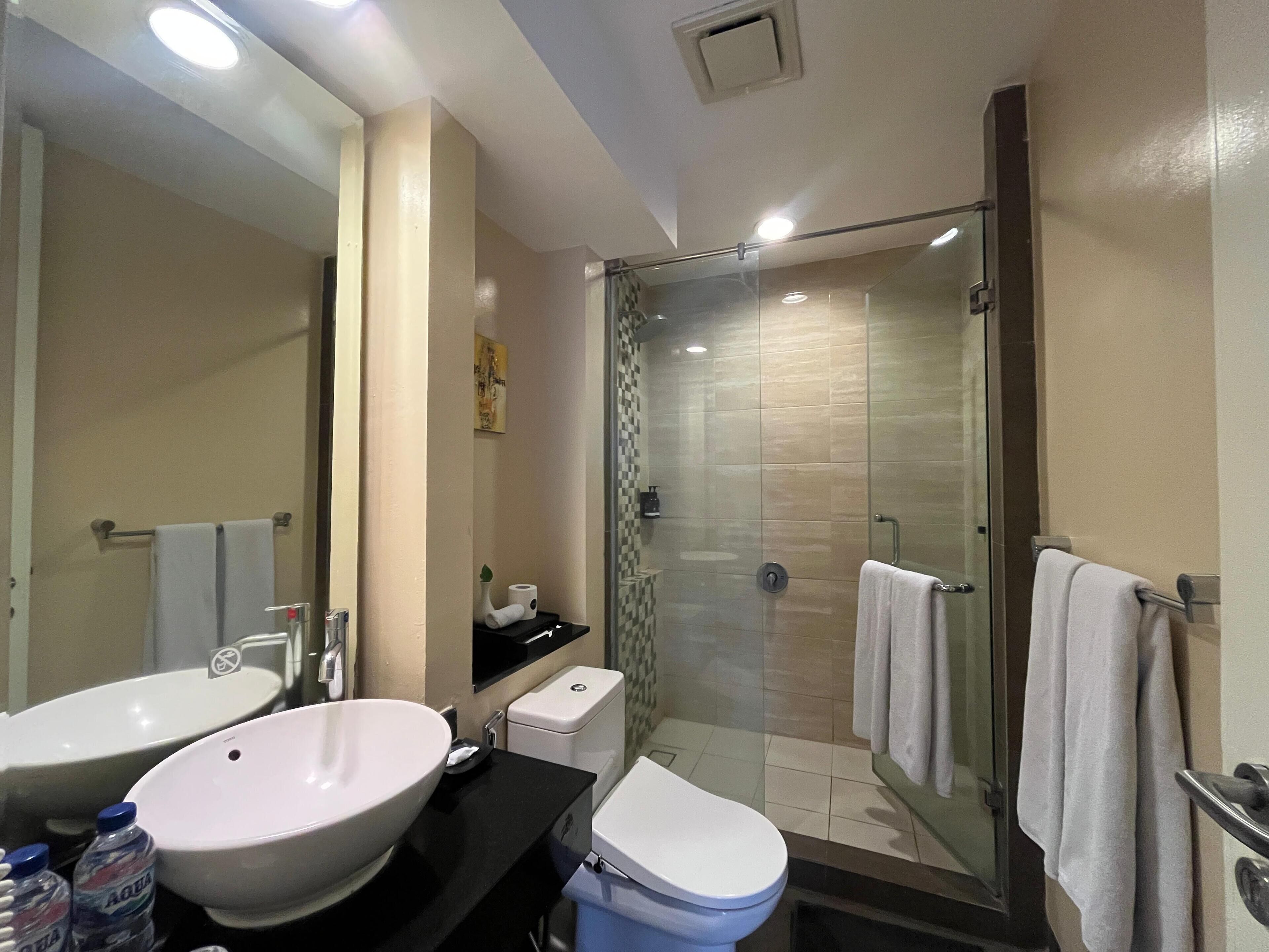 A modern bathroom with a glass-enclosed shower, a large white sink, and a toilet.