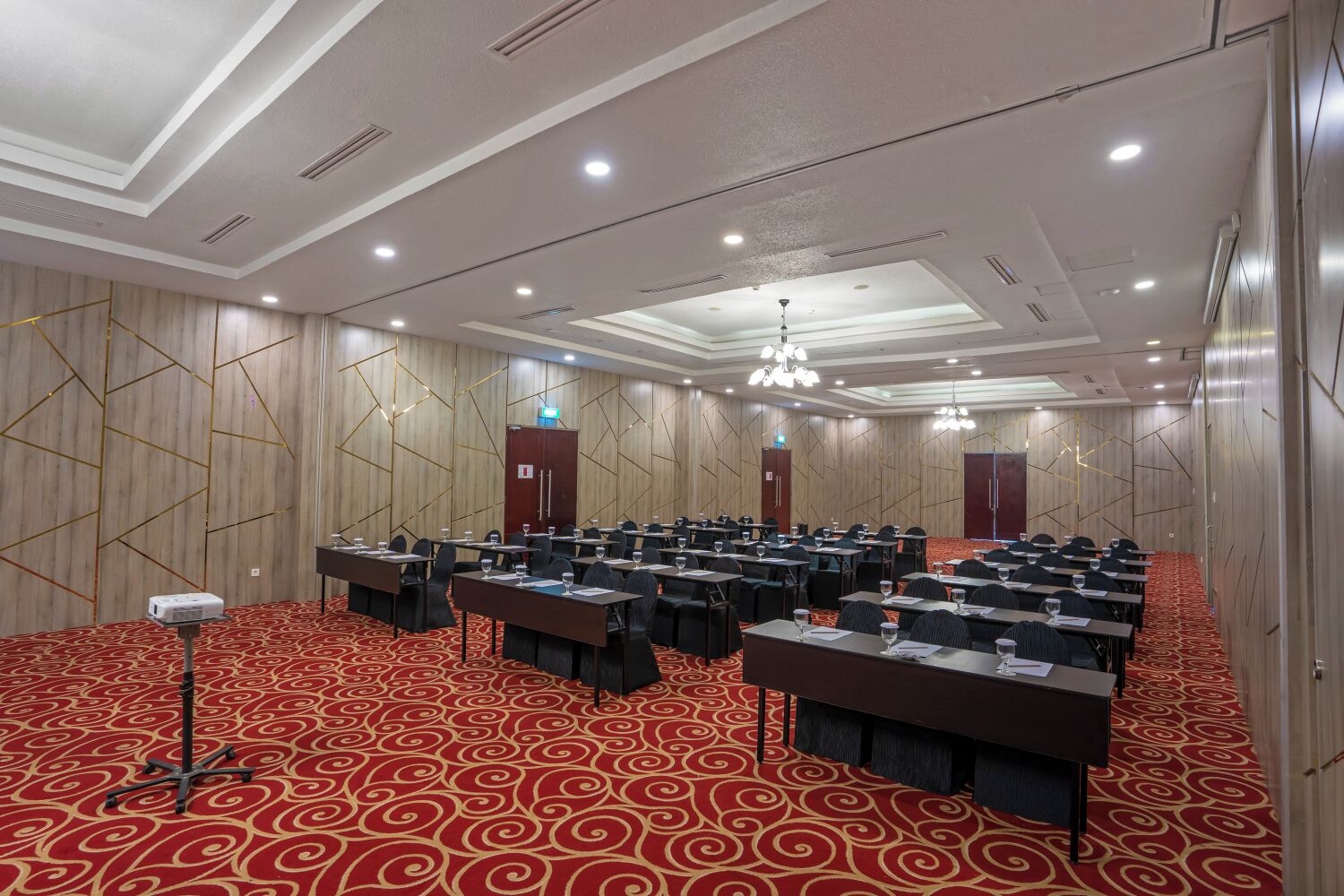 A conference room with multiple tables, chairs, and a red carpeted floor.