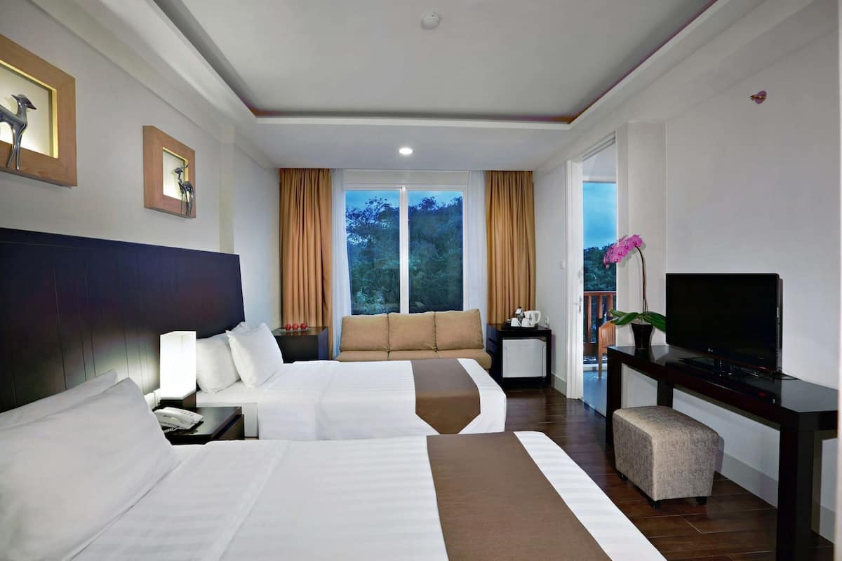 A hotel room with two beds, a TV, a small table, a sofa, and a balcony with a view.