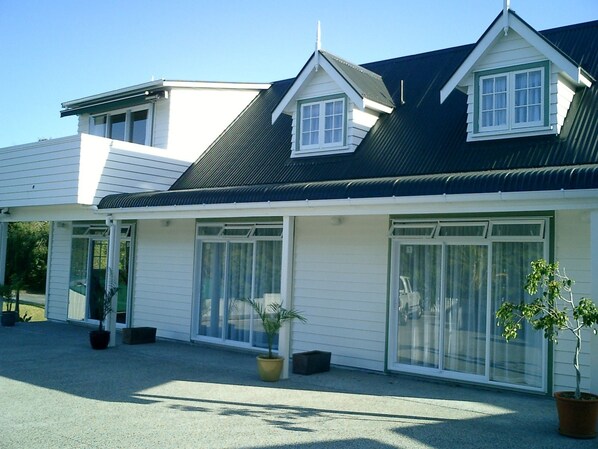 A two-story building with a gabled roof, large windows, and potted plants.