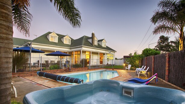 A backyard with a swimming pool, hot tub, and lounge chairs. - Warkworth Lodge (Warkworth)