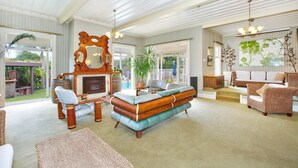 A spacious living room with a large sofa, a fireplace, and a view of the outdoors. - Warkworth Lodge (Warkworth)