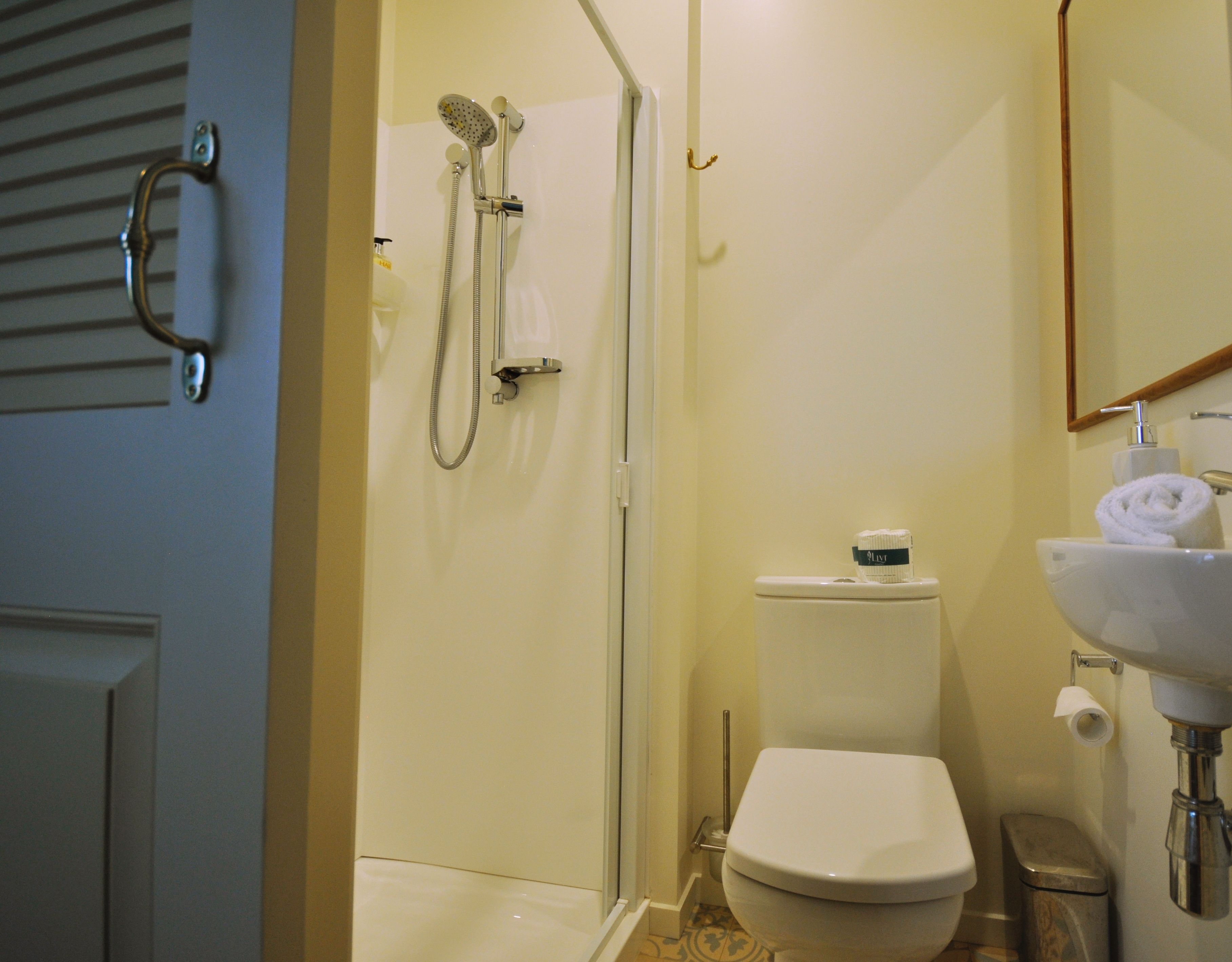 A bathroom with a shower, toilet, sink, and a towel hanging on the wall.