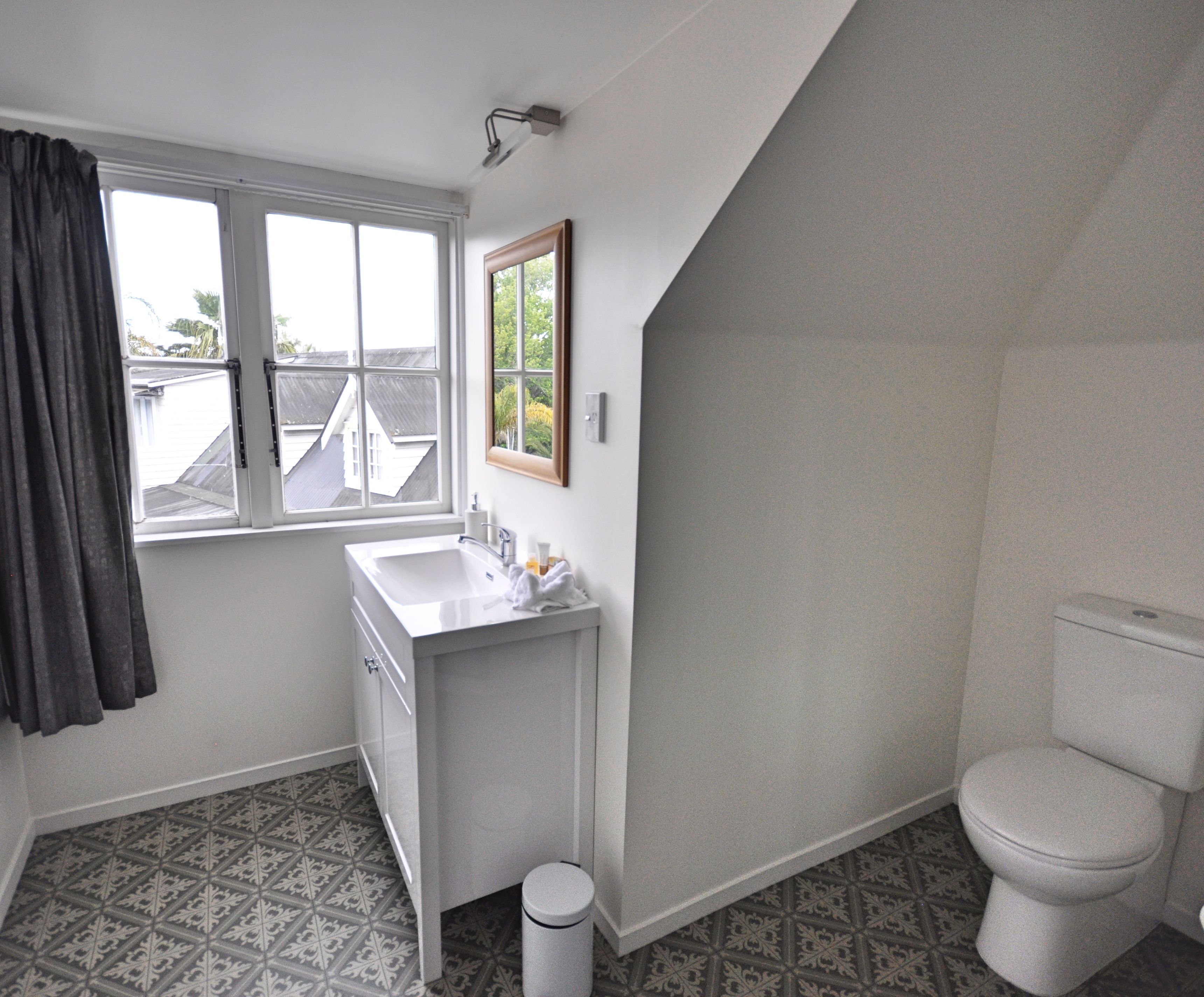 A bathroom with a white sink, a toilet, and a window with curtains.