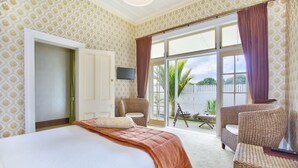 A hotel room with a large bed, a wicker chair, a small table, and a TV. - Warkworth Lodge (Warkworth)