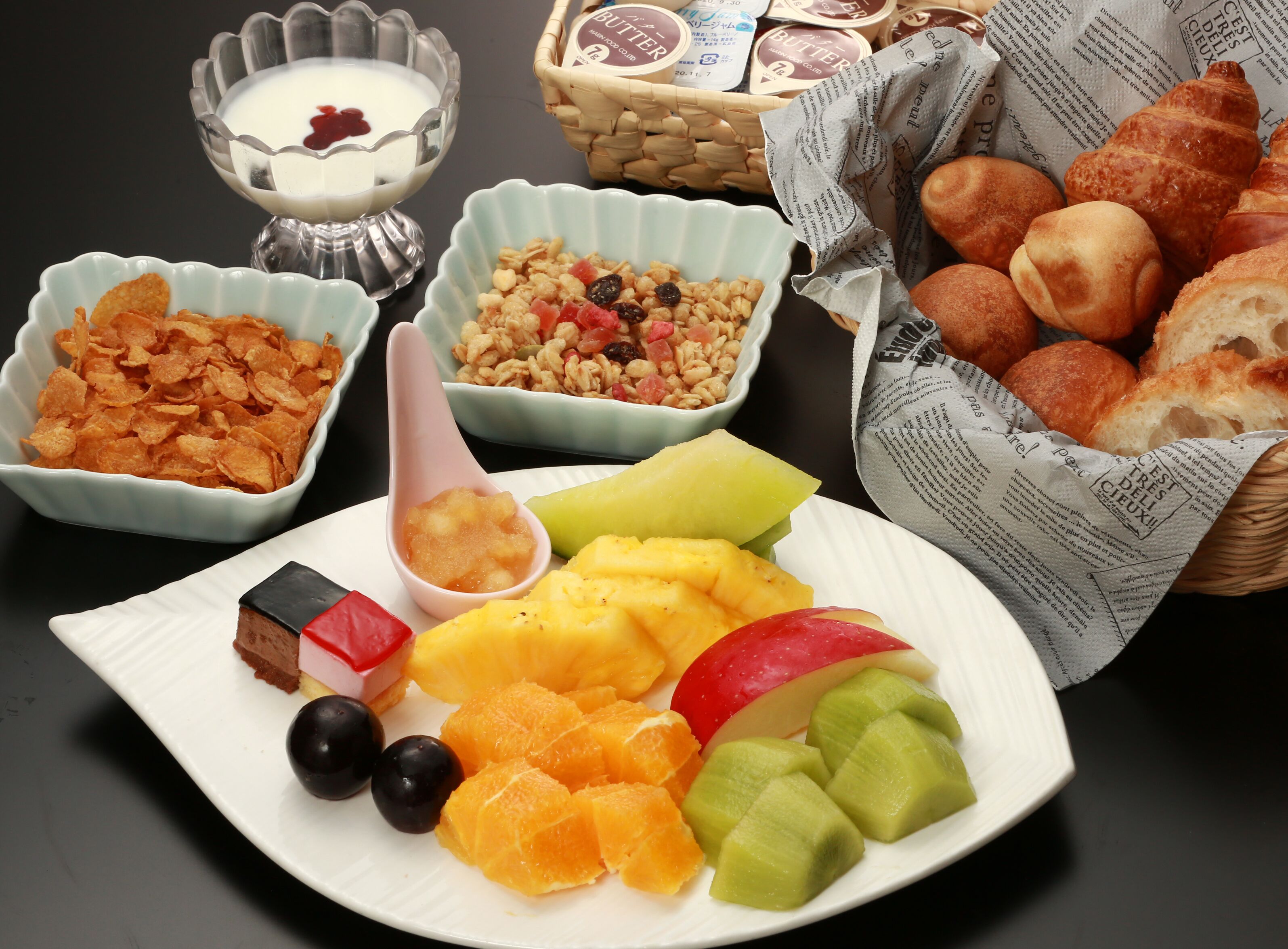 A breakfast setting with cereal, yogurt, fruit, and pastries.