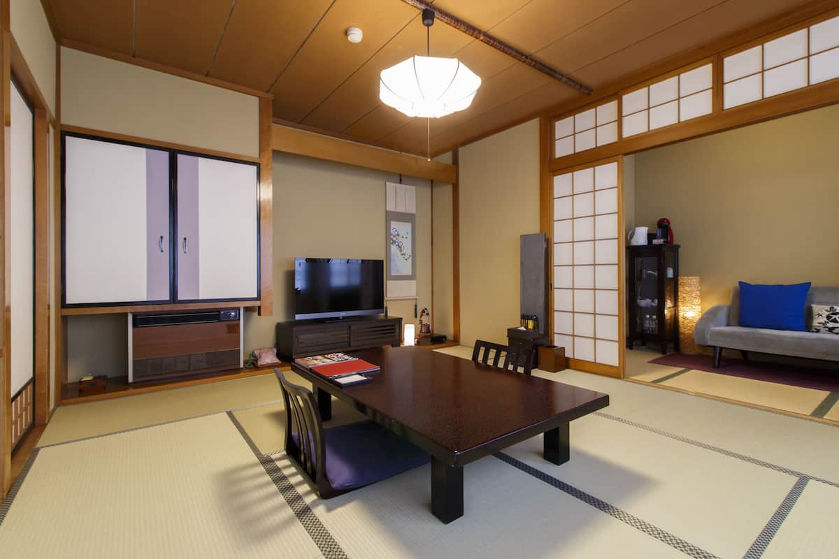 Una habitación tradicional japonesa con suelo de tatami, una mesa baja y un televisor.
