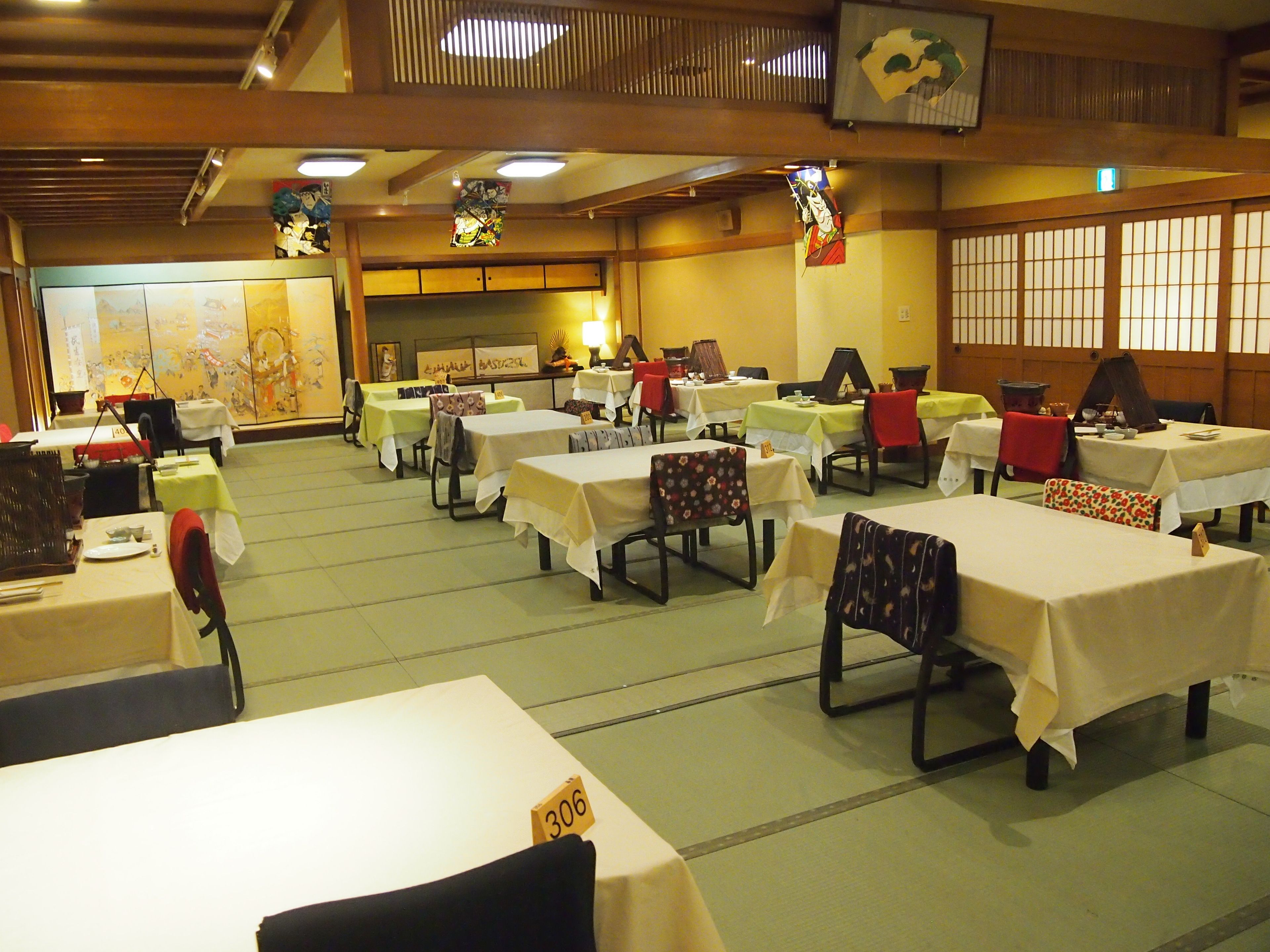 A banquet hall with multiple tables and chairs, some with table numbers visible.