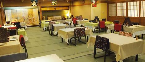 A banquet hall with multiple tables and chairs, some with table numbers visible.