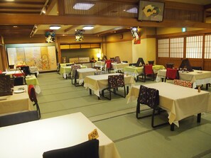 Une salle de banquet avec de nombreuses tables et chaises, dont certaines portent des numéros de table.