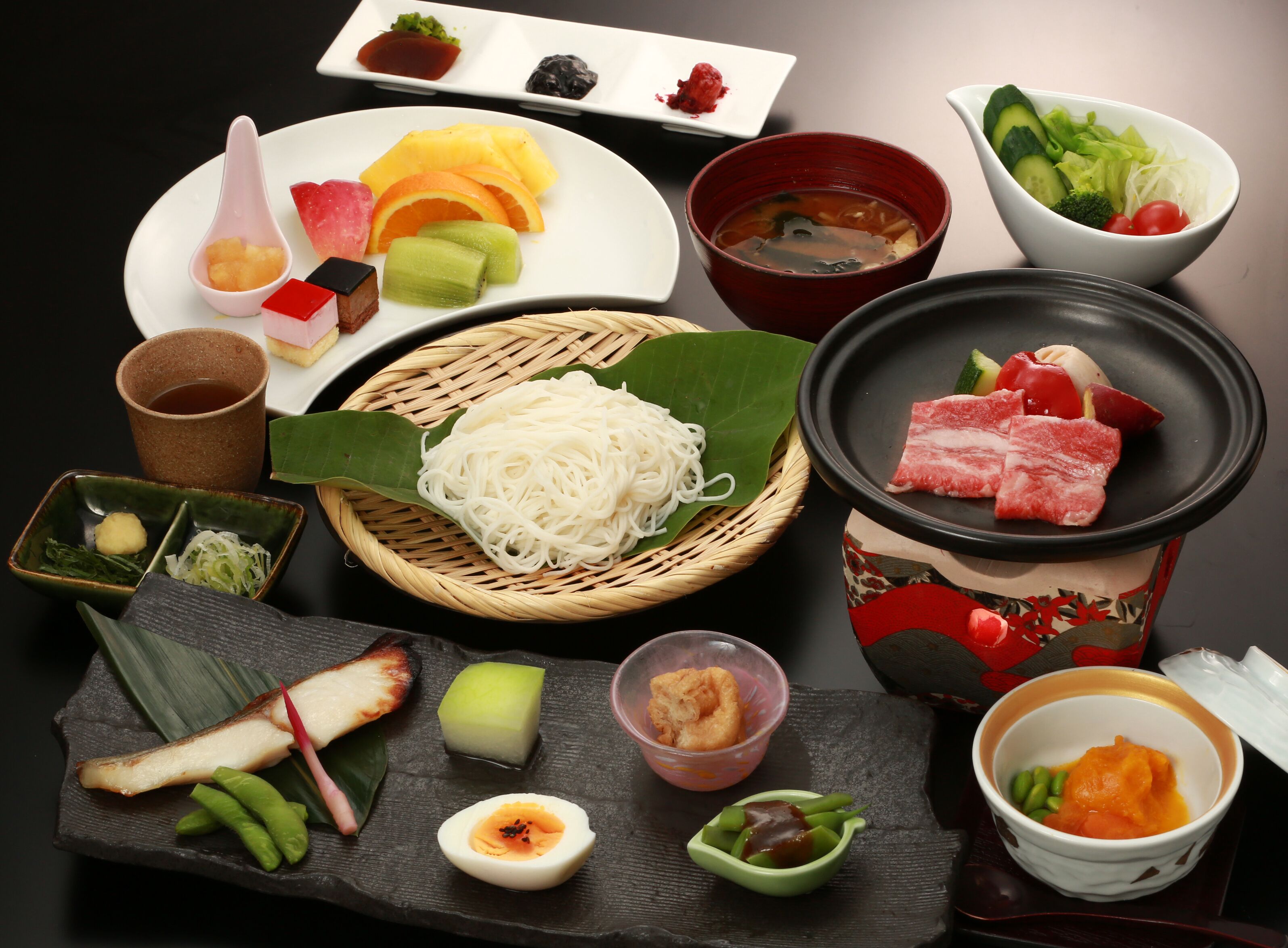 A variety of Japanese dishes including sushi, sashimi, and noodles, arranged on a table.
