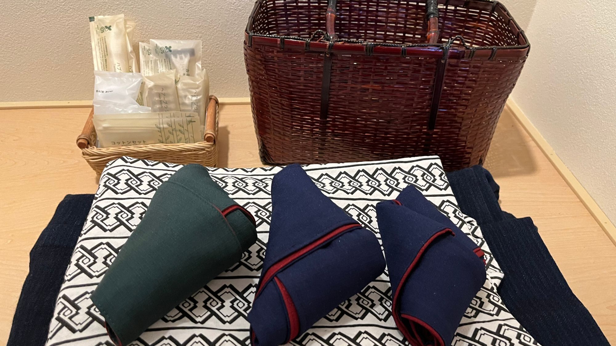 Una cama con un cojín estampado y dos mantas dobladas.