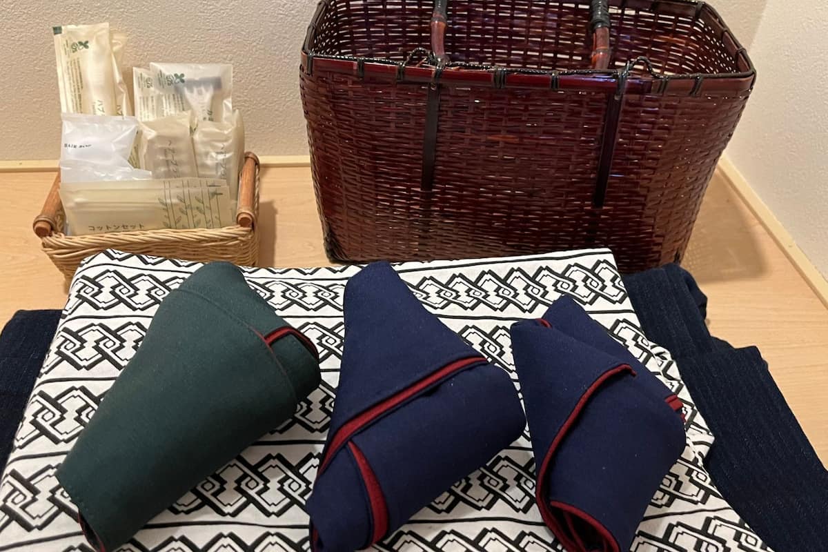 Una cama con un cojín estampado y dos mantas dobladas.