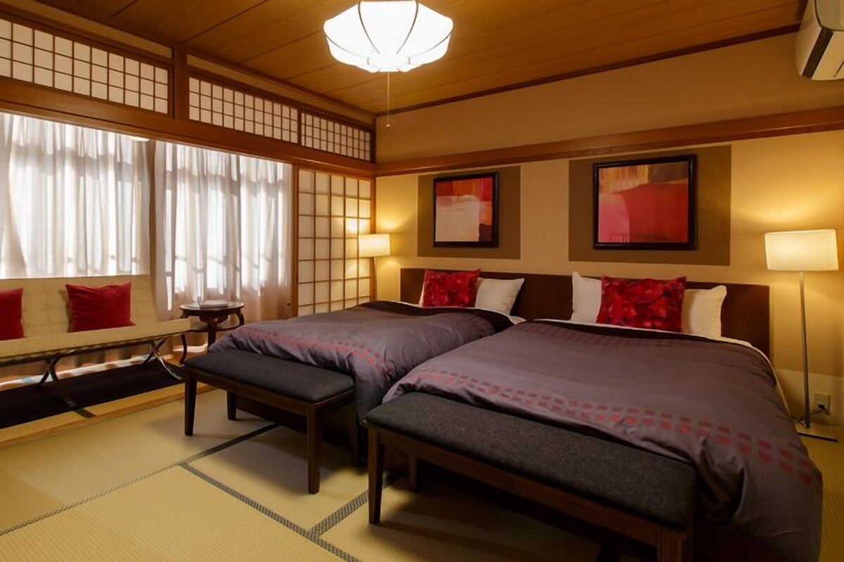 Een traditionele Japanse hotelkamer met tatami vloeren, een futon bed, een shoji scherm en een schuifdeur.