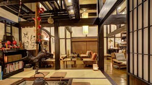 Un interior japonés tradicional con suelo de tatami, mobiliario de madera y una disposición para ceremonia del té.