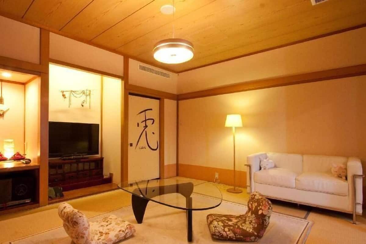 Una sala de estar con sofá, una mesa de centro de vidrio, televisor y una pared decorativa con caligrafía.