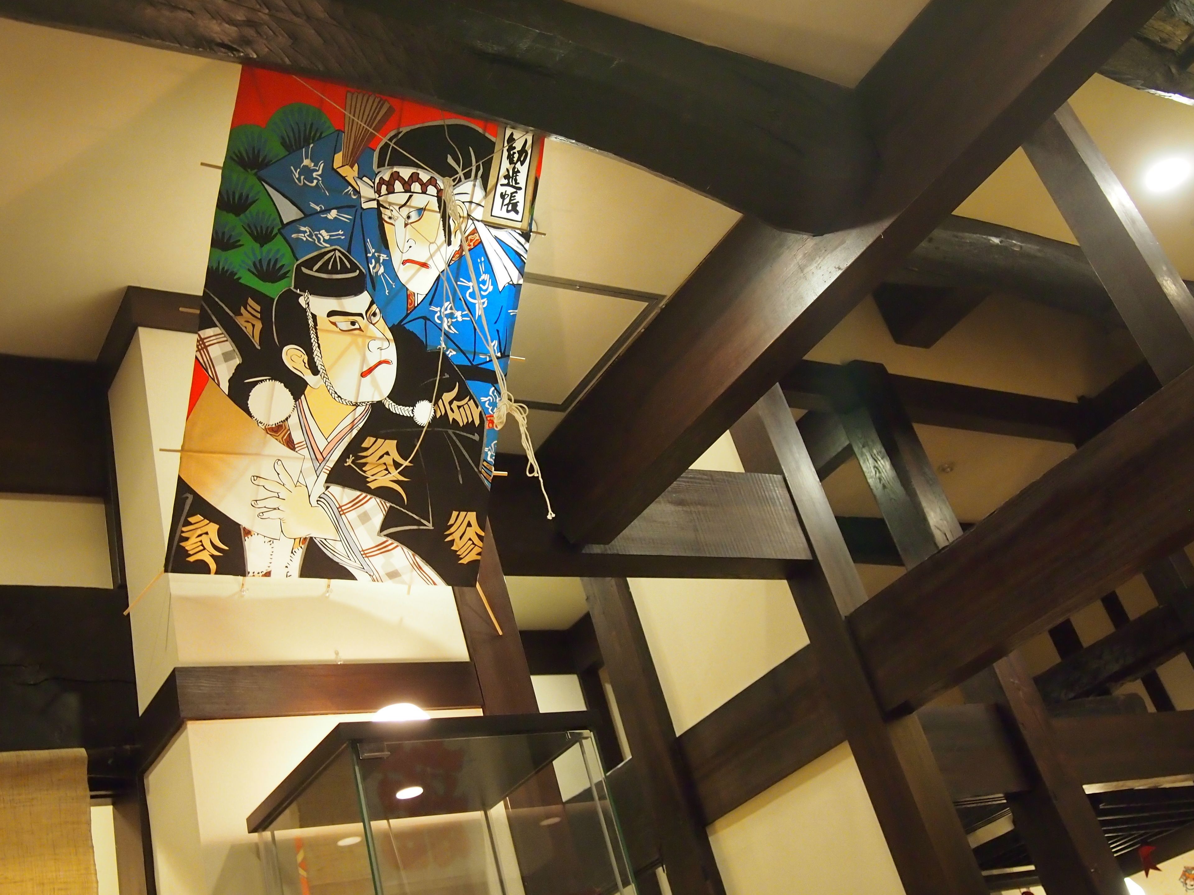 A traditional Japanese artwork on a wall with a modern architectural structure in the background.
