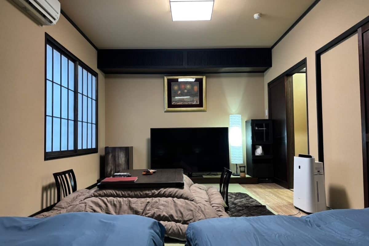 Habitación de hotel con cama, escritorio, silla, televisor y refrigerador.