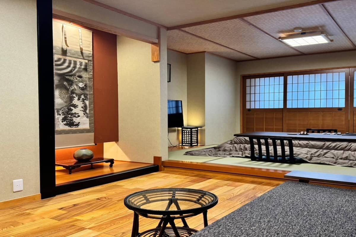 Una habitación tradicional japonesa con suelo de tatami, una mesa baja y un futón.