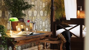 A wooden desk with a lamp, a potted plant, a metal container, and a magazine. - Strandflickornas Havshotell (Lysekil)