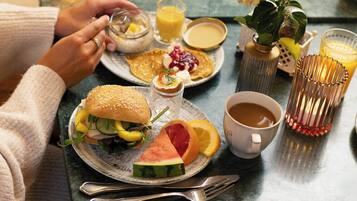 Una escena de desayuno con un plato de comida, una taza de café y un vaso de zumo de naranja.