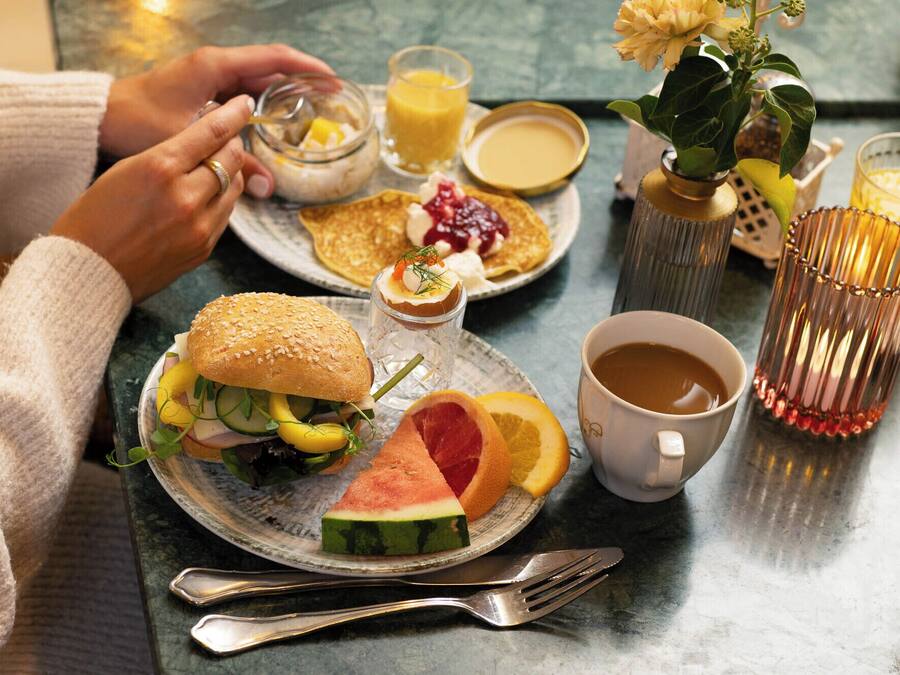 Una escena de desayuno con un plato de comida, una taza de café y un vaso de zumo de naranja.