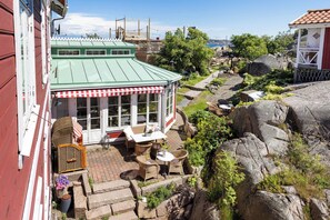 A covered outdoor seating area with wicker furniture, a stone pathway, and a view of the sea. - Strandflickornas Havshotell (Lysekil)