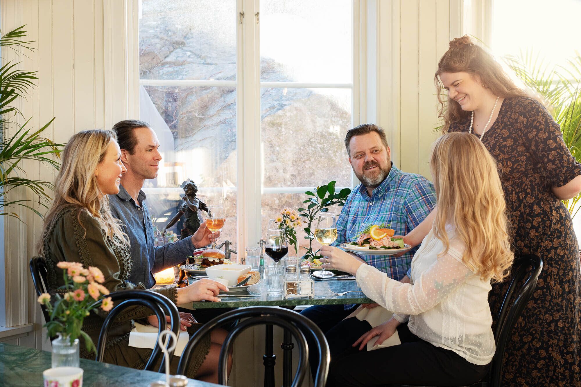 Un grupo de personas cenando en una mesa con vistas al exterior.
