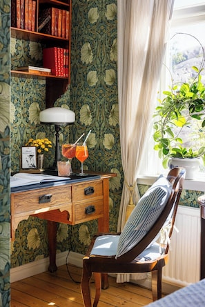 A cozy room with a wooden desk, a chair, a bookshelf, and a window with a plant. - Strandflickornas Havshotell (Lysekil)